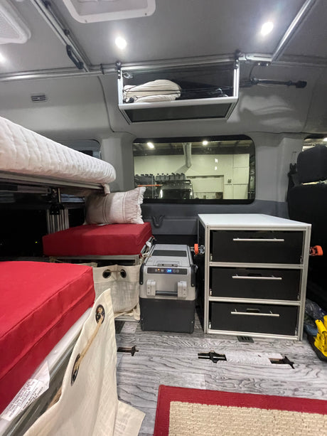 RV rental interior features bunk beds, a portable fridge displaying 34F, and ample storage drawers for a comfortable journey.