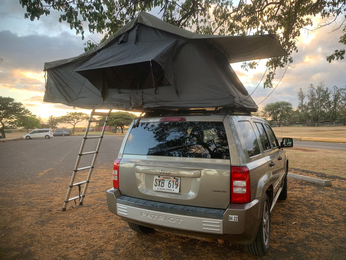 Explore with this compact RV rental: a Jeep Patriot SUV with a deployed rooftop tent and ladder, ideal for sunset camping. — photo 12