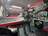 Functional RV rental interior with bunk bed, seating, and organized storage including gear for paragliding.