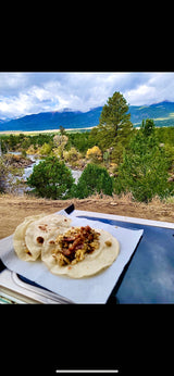 Breakfast tacos with a scenic mountain and river backdrop from an RV rental. Perfect outdoor meal!
