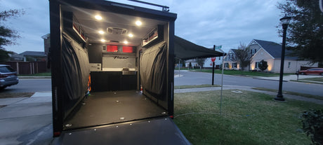 An RV rental with its rear open, revealing a compact kitchen, storage, & an extended awning. Ready for your next outdoor adventure.