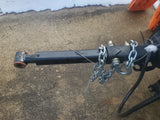 RV rental trailer hitch with safety chains on concrete pavement, featuring attachment bolts and a safety cable. Snow is present.