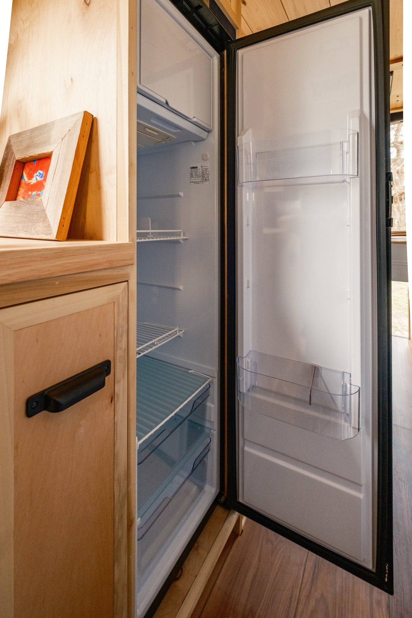 RV rental: Bright, open refrigerator with clear door bins and wire shelves, integrated into light wood cabinetry, ready for your trip. — photo 12