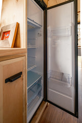 RV rental: Bright, open refrigerator with clear door bins and wire shelves, integrated into light wood cabinetry, ready for your trip.