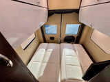 Inside this spacious RV rental: two plush beige sleeping/lounge benches, overhead cabinets, and rear windows for light.