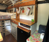 Cozy RV rental interior with a functional kitchenette, bed, and smart storage, perfect for road trips and tiny living.