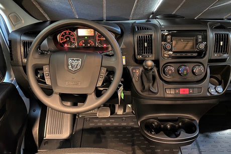RV rental Dodge Ram ProMaster van dashboard shows the steering wheel, infotainment screen, climate controls, and gear shifter.