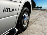 ATLAS RV rental with shiny chrome wheel parked on a sandy beach, ready for adventure. A perfect travel companion.