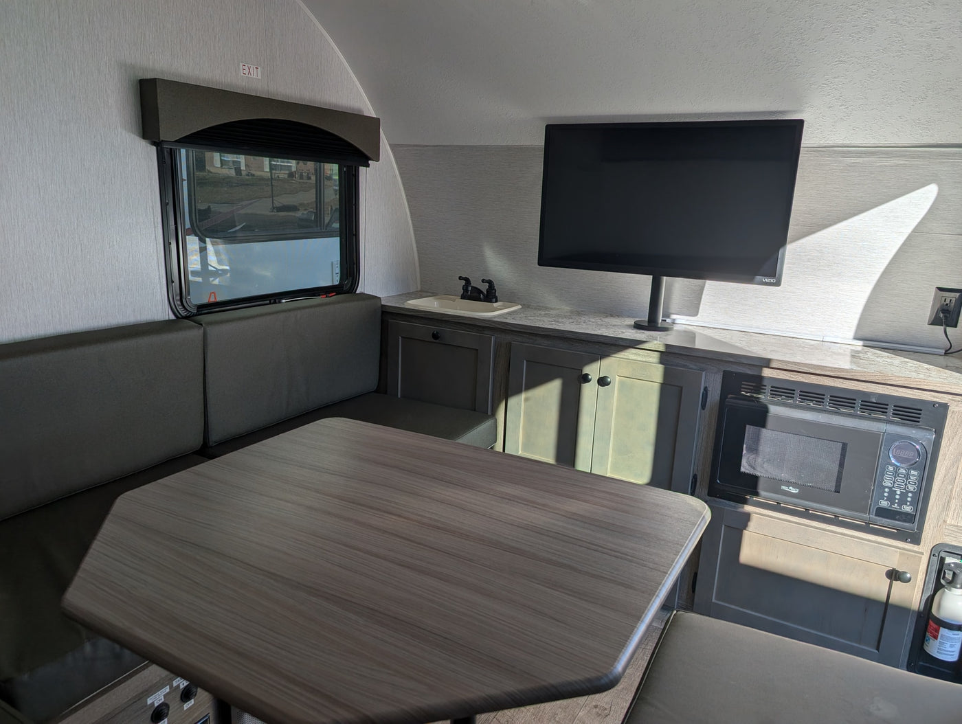 Cozy RV rental interior: Dinette, TV, and kitchenette with sink/microwave, ready for your adventure. — photo 18