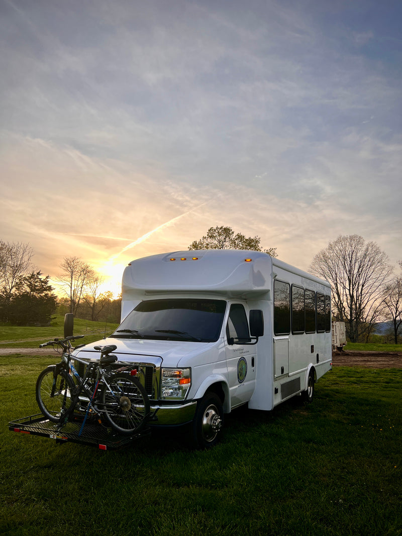 White RV rental with front-mounted bikes, parked on green grass at sunset. Ideal for outdoor adventures. — photo 20