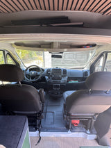 RV rental. Interior view of a camper van's front cabin: dashboard, steering wheel, and seats.