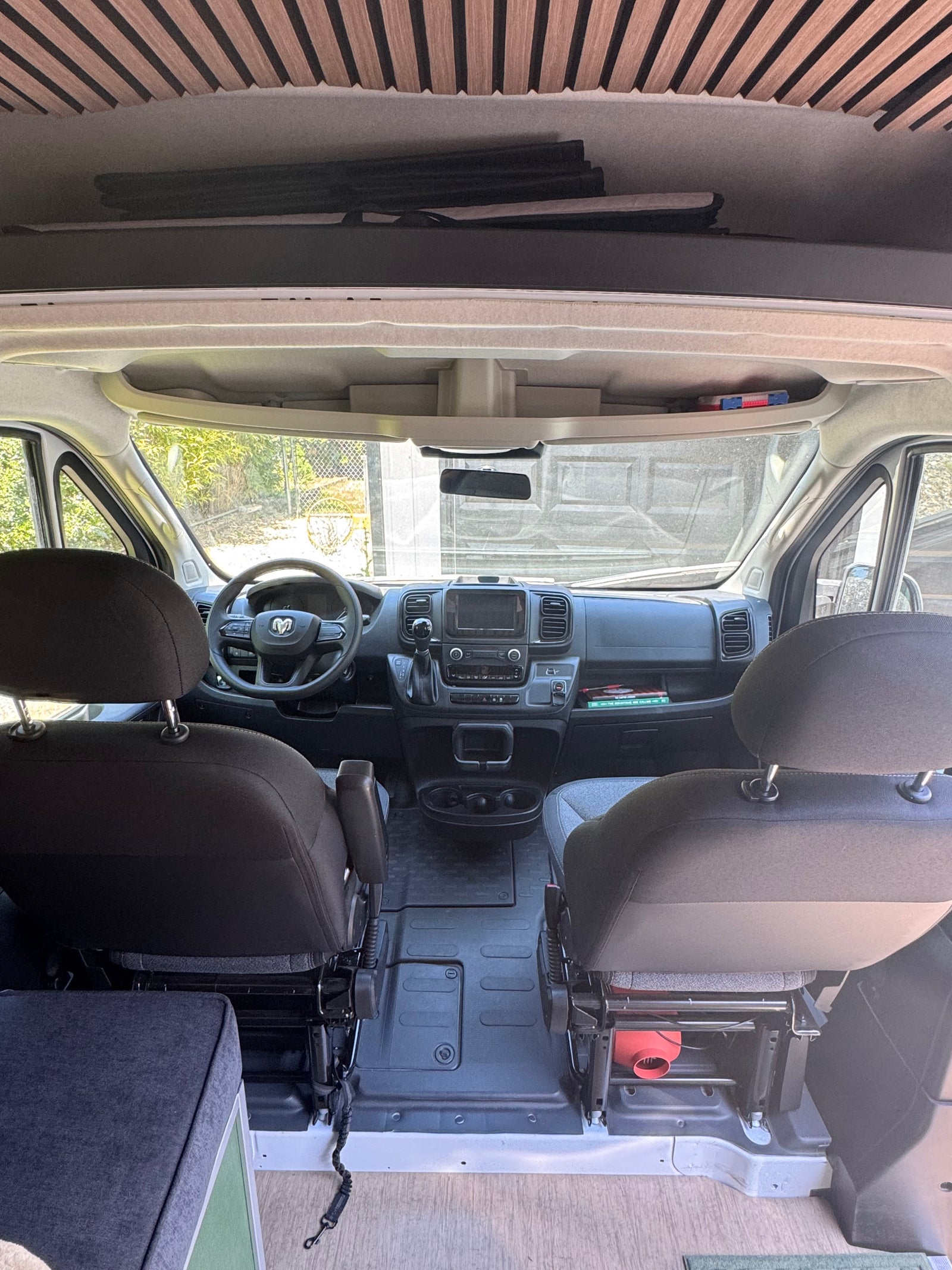 RV rental. Interior view of a camper van's front cabin: dashboard, steering wheel, and seats.