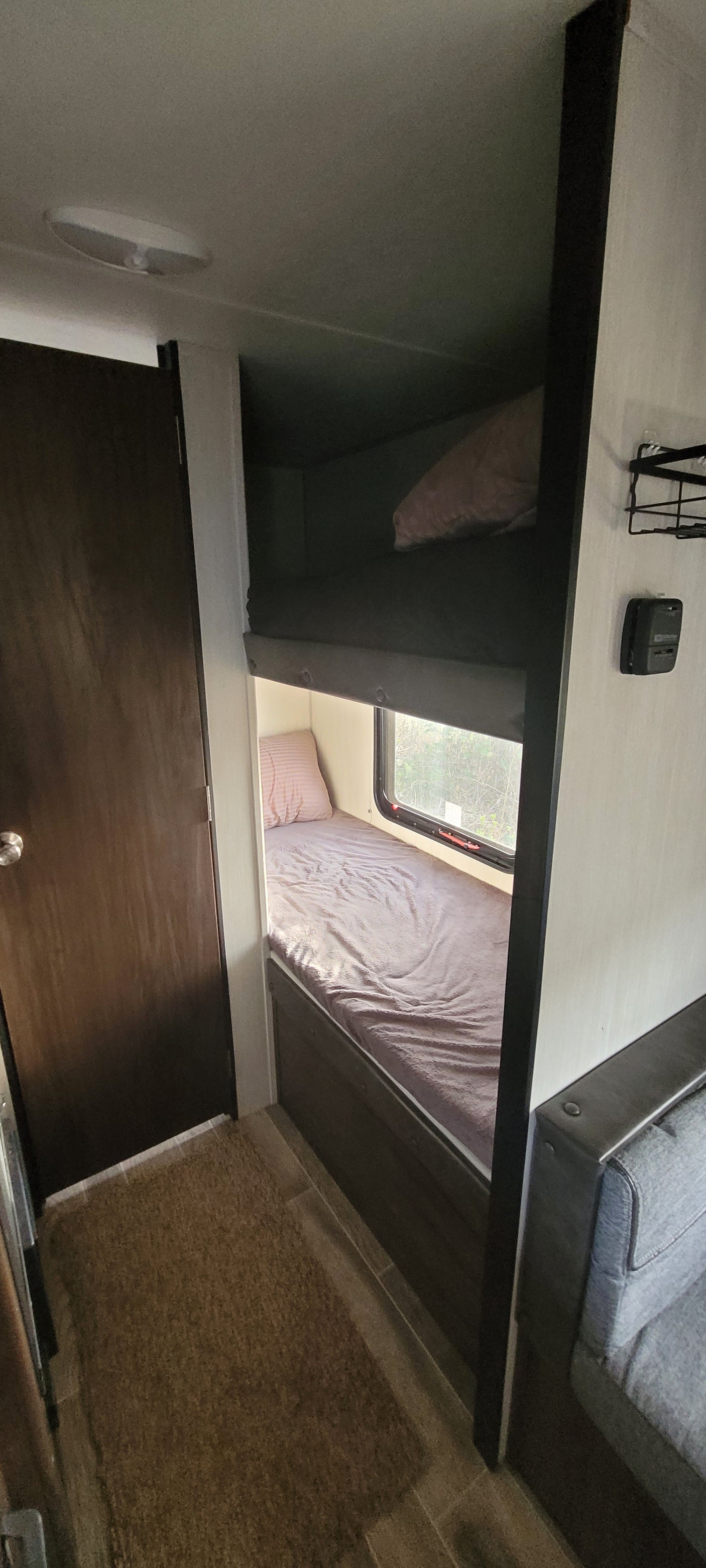 RV rental interior. Two bunk-style sleeping areas, one with bedding and a window, the other a darker storage alcove.
