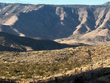Breathtaking desert mountains with rugged peaks and sparse flora. An RV rental offers exploration of this vast, sunlit landscape.
