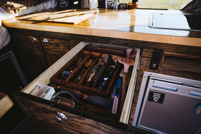 Inside an RV rental: a neat kitchen drawer with utensils & an Aeropress, next to a Dometic fridge. Efficient camper storage. — photo 7