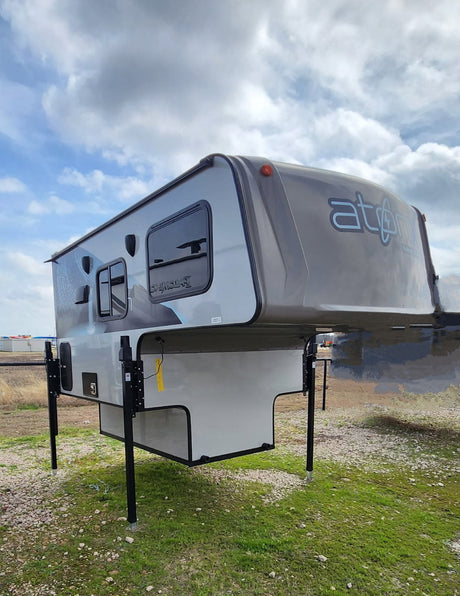 Grey Atom truck camper, a versatile RV rental option ready for outdoor adventures. Equipped with sturdy jacks.