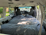 Cozy RV rental camper van interior: a made bed and front cockpit visible, ideal for custom travel adventures.