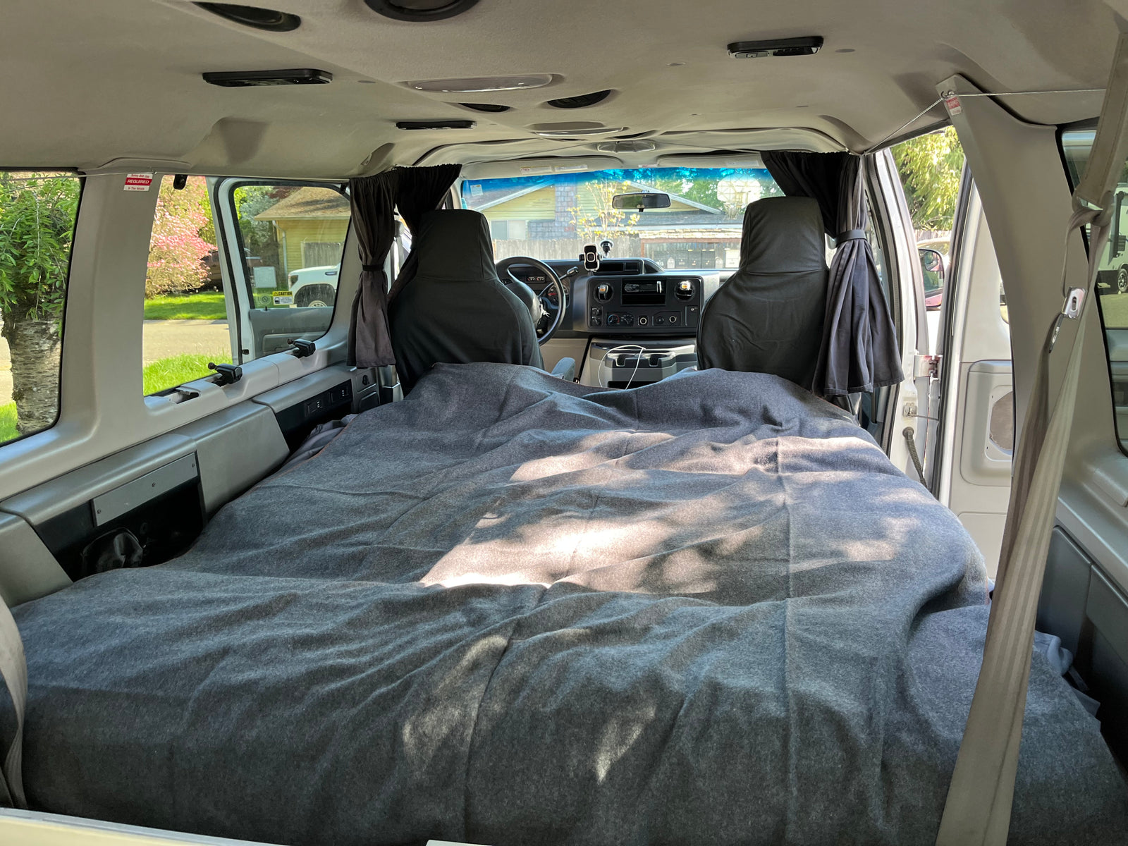 Cozy RV rental camper van interior: a made bed and front cockpit visible, ideal for custom travel adventures.
