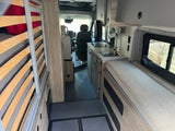 Inside this RV rental: a compact kitchen, comfortable bench seating, and slatted bed frame, ready for your next trip.