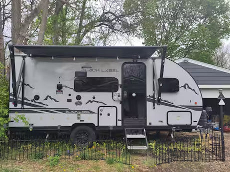 Stylish light gray rv rental travel trailer with an extended awning and mountain graphics, parked for your next adventure.