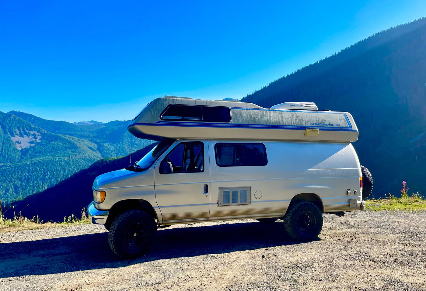  parked in a dark forest against a twilight sky. Peaceful camping journey.|Silver Airstream camper van on a dirt road — photo 3