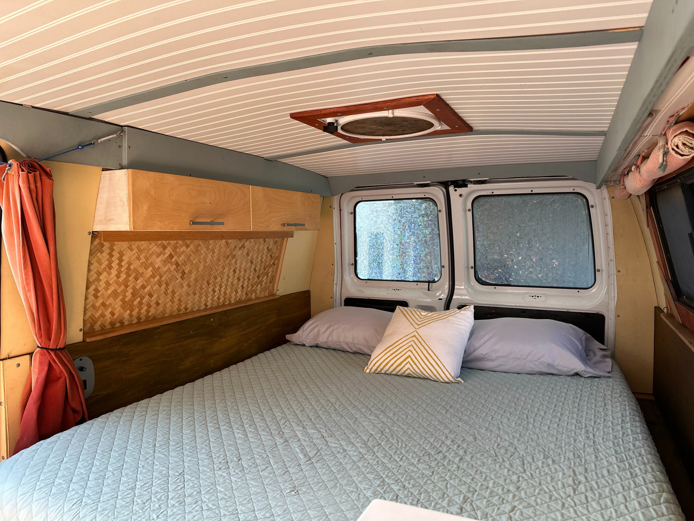 Step inside this inviting RV rental. A comfortable bedroom setup with a quilted bed, wooden cabinetry, and textured ceiling.