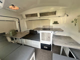 RV rental interior showcasing a bright, functional space with convertible dinette, kitchenette, and ample storage.
