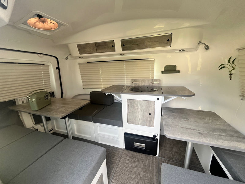 RV rental interior showcasing a bright, functional space with convertible dinette, kitchenette, and ample storage. — photo 17