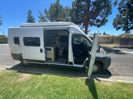 White camper van with open doors parked on a sunny street, ready for adventure. Ideal for an rv rental.