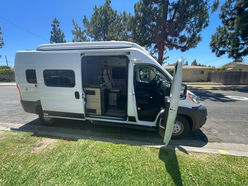  parked curbside on a sunny residential street. Equipped with windows & roof AC.|White camper van with open doors parked on a sunny street — photo 10