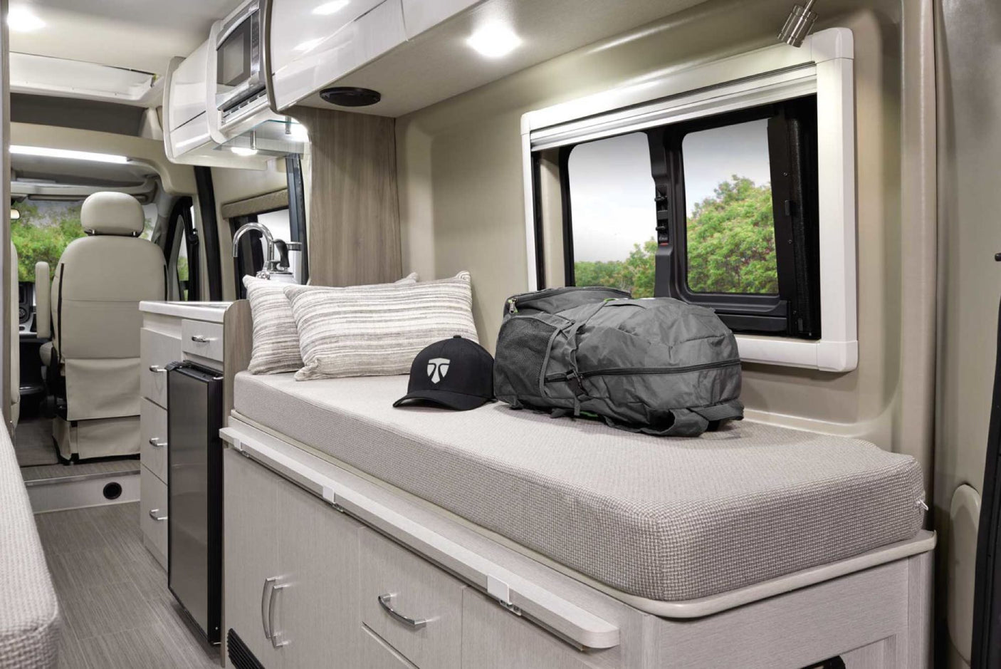 Spacious RV rental interior featuring a cozy living area with a bench, kitchen, microwave, and fridge. Perfect for mobile adventures.