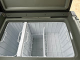 RV rental essential: Open portable fridge/freezer, showing dual compartments with wire baskets and interior light for camping.