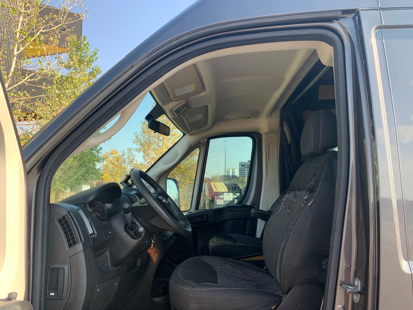 View of an RV rental van's driver's side interior, showing the steering wheel, dashboard, and worn seat.