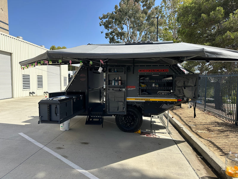 Explore with this robust Conqueror off-road camper. Perfect for rv rental, it features an outdoor kitchen & large awning setup. — photo 5