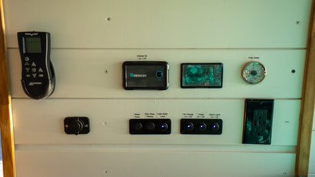 This RV rental control panel features a MaxxAir remote, Renogy power displays for battery/inverter, water gauge, and switches for essential utilities.