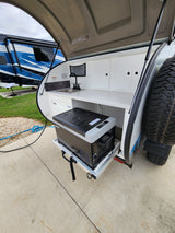 This rv rental teardrop camper's outdoor kitchen features a sink, faucet, and pull-out portable refrigerator.