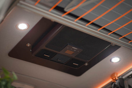 RV rental interior featuring a Dometic ceiling-mounted AC unit, integrated lights, and overhead solar panel details.