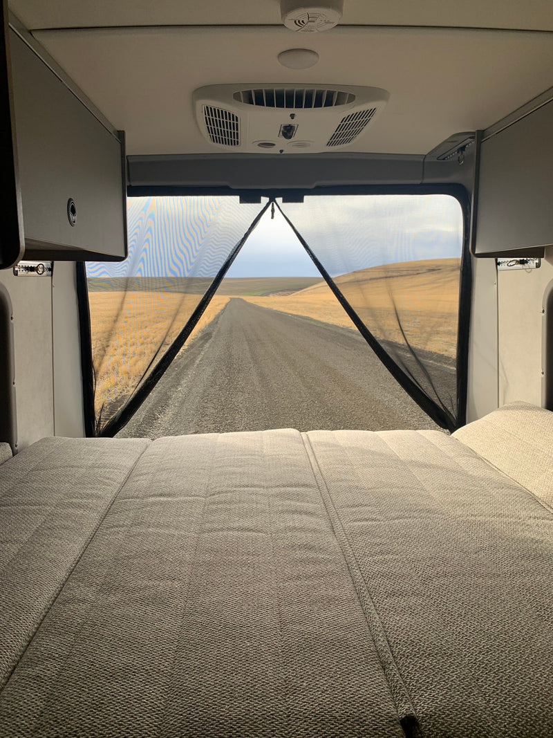  ideal for RV rental adventures. Parked in a scenic field under cloudy skies.|Front view of a grey Winnebago RV rental on a dirt road — photo 4