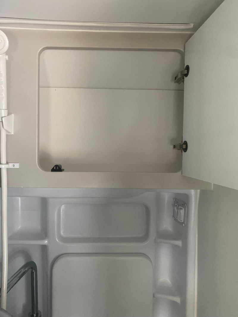 RV rental: Compact white bathroom featuring a shower, open cabinet, and molded basin. — photo 15