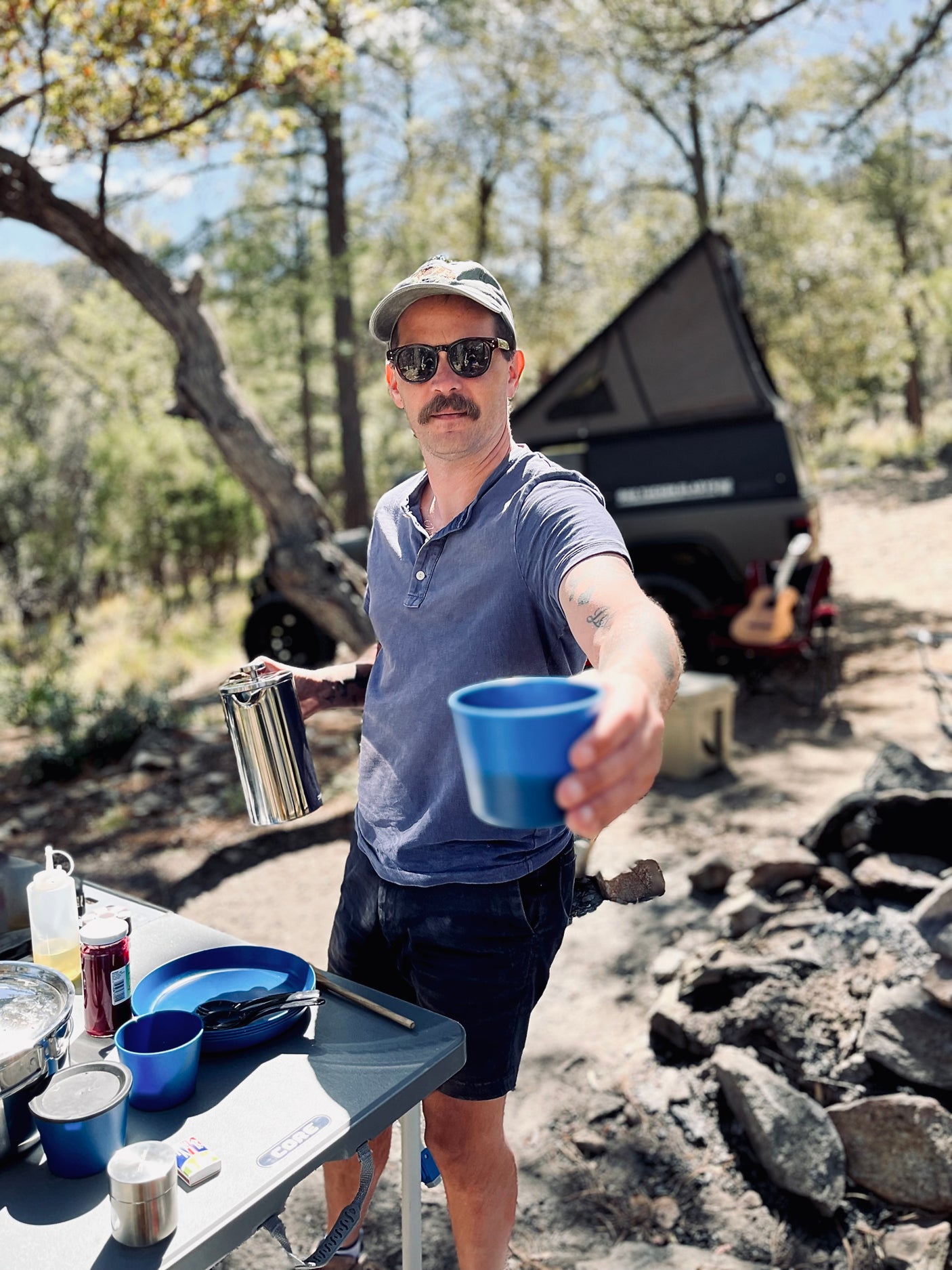 Man offers coffee from his RV rental camp kitchen setup. Ideal for outdoor cooking & adventure trips.