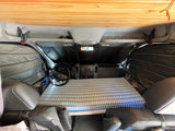 RV rental camper van interior: A front bed occupies the cockpit area, complete with a dashboard and insulated window shades.