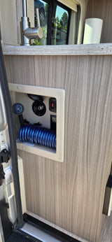 RV rental: Compact kitchen, modern faucet & counter. Lower utility panel offers outdoor shower, water hookup, and pump controls.
