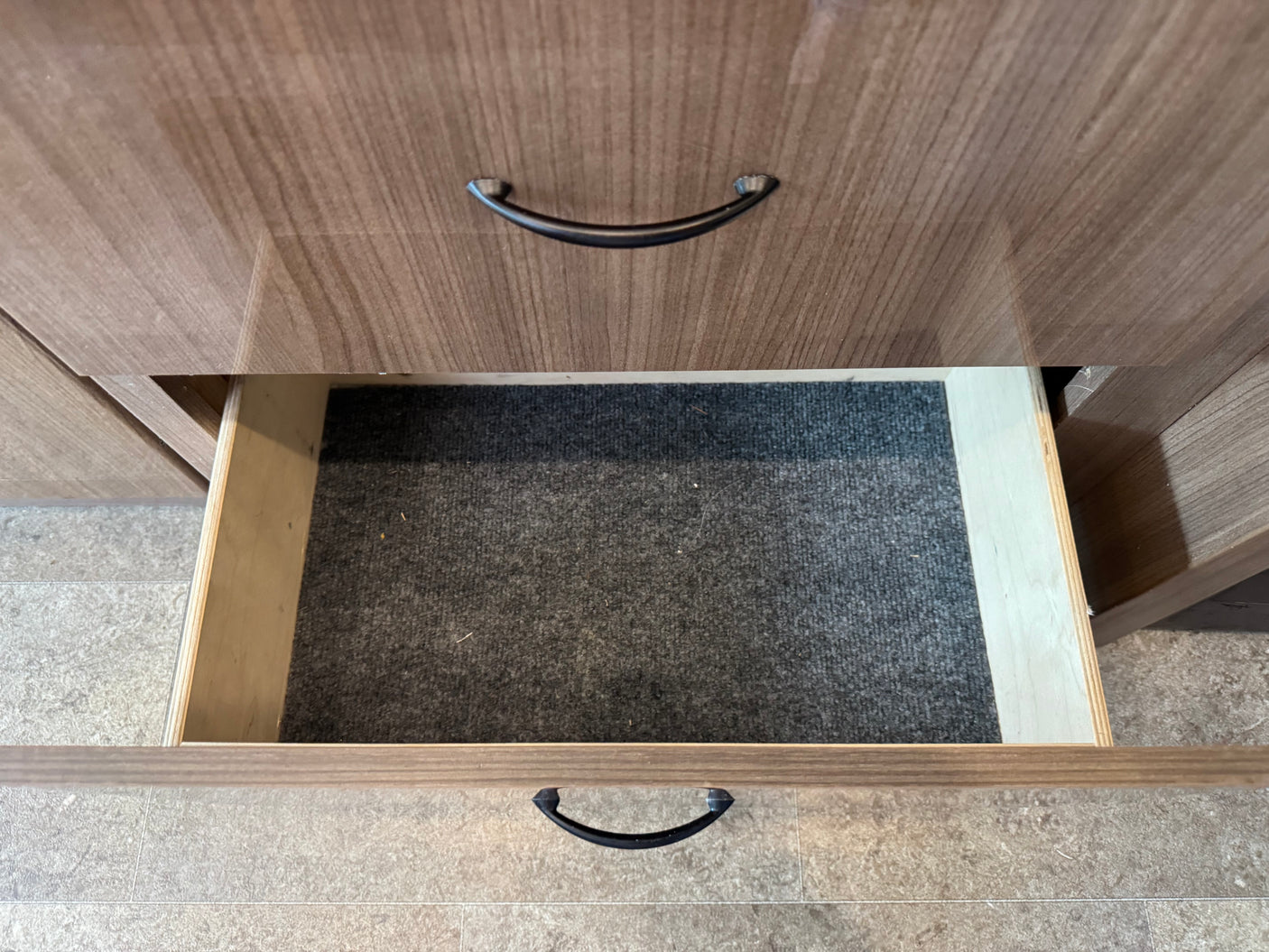 Inside an RV rental: An open drawer with a dark gray carpet liner, below a closed drawer, offering practical storage.