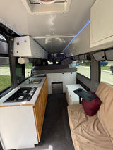 Inside this RV rental, discover a compact kitchen with stove & sink, bed, fridge, and comfortable seating for your travels.