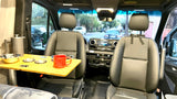 Cozy RV rental interior with swiveling front seats, a versatile table, and coffee setup. Perfect for camper van adventures.