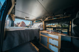 Experience van life in this RV rental. Comfy bed, functional kitchen, & stunning desert scenery outside.