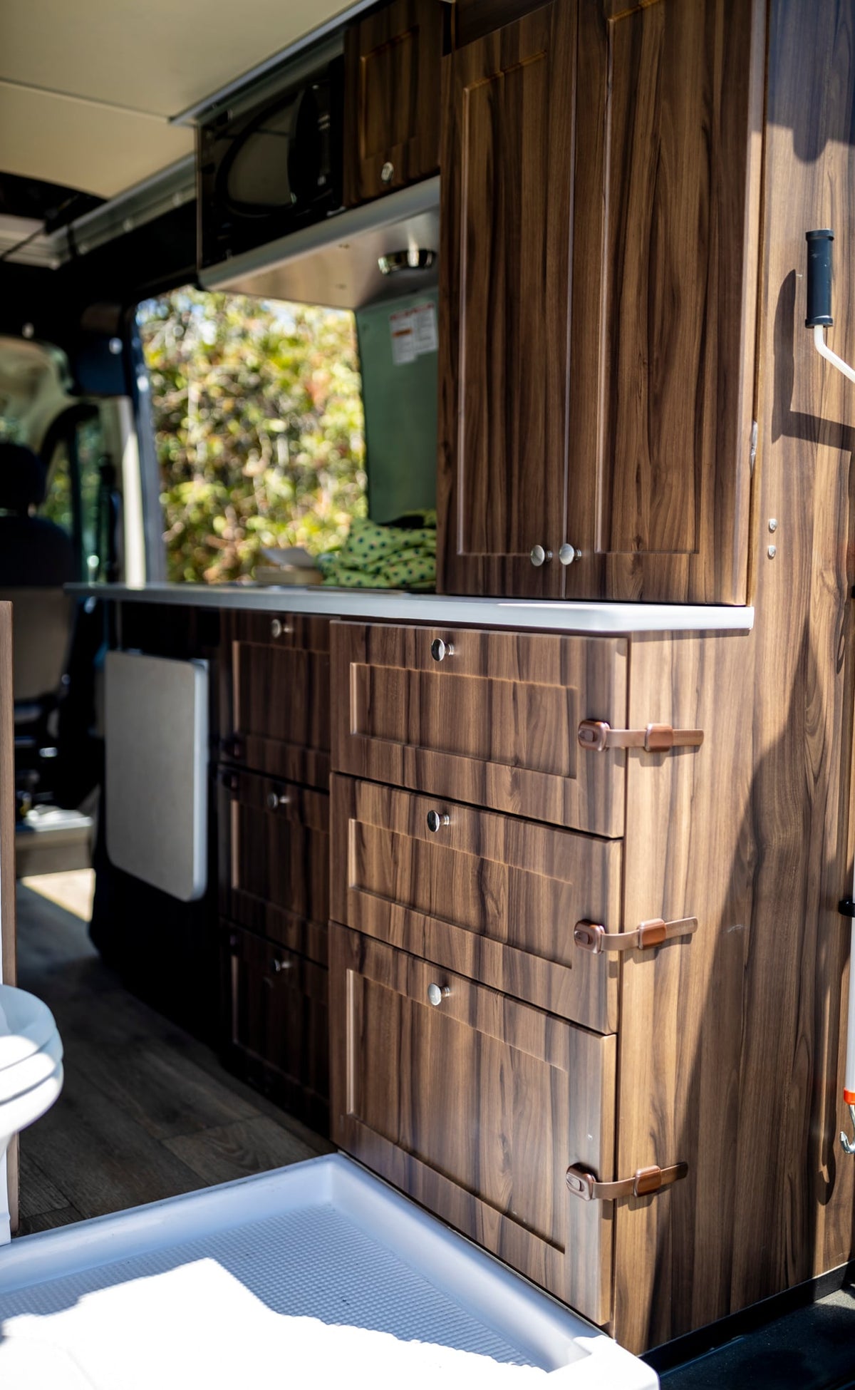  and dark cabinets. Enjoy beach views from the windows.|Woman cooking breakfast in a modern RV rental. Her cozy camper van kitchen is perfect for road trip adventures.|Stocking the compact refrigerator in an RV rental with fresh eggs — photo 20