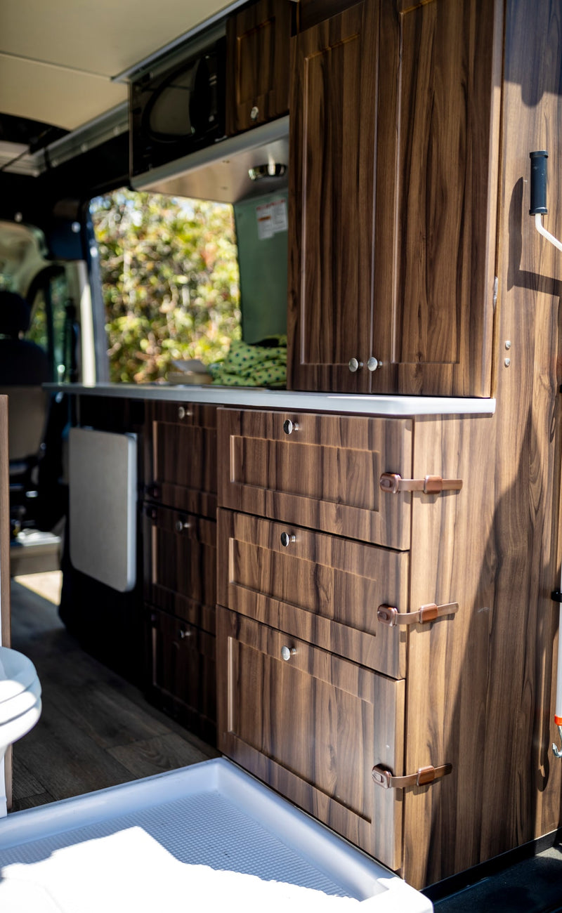  and dark cabinets. Enjoy beach views from the windows.|Woman cooking breakfast in a modern RV rental. Her cozy camper van kitchen is perfect for road trip adventures.|Stocking the compact refrigerator in an RV rental with fresh eggs — photo 20