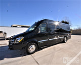 Sleek black Airstream Sprinter van RV rental, ready for adventure. Parked on concrete under a clear sky.