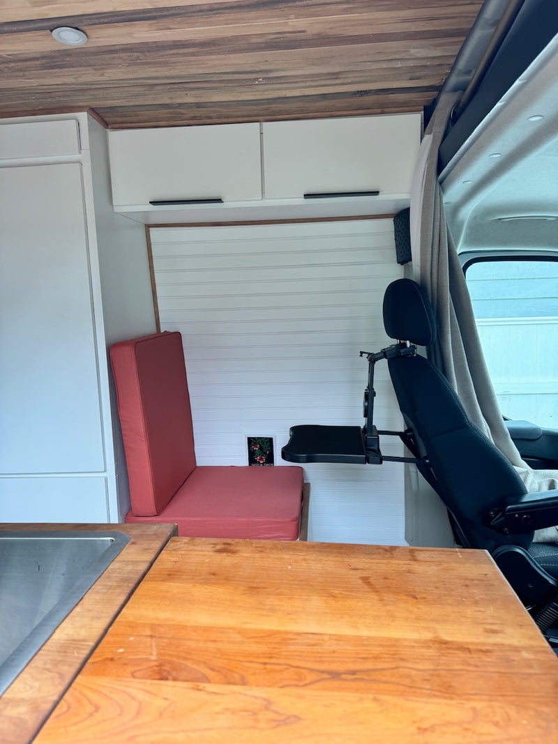  and seating area in a wood-paneled camper van.|White RV rental van on a vibrant hillside covered in yellow wildflowers — photo 6